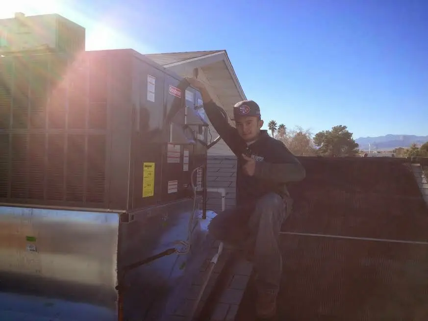 HVAC technician performing Air Duct Repair on a rooftop unit in Derry